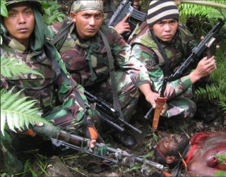 Indonesian soldiers pose for a trophy photo after murdering a tribal leader in the West Papua highlands